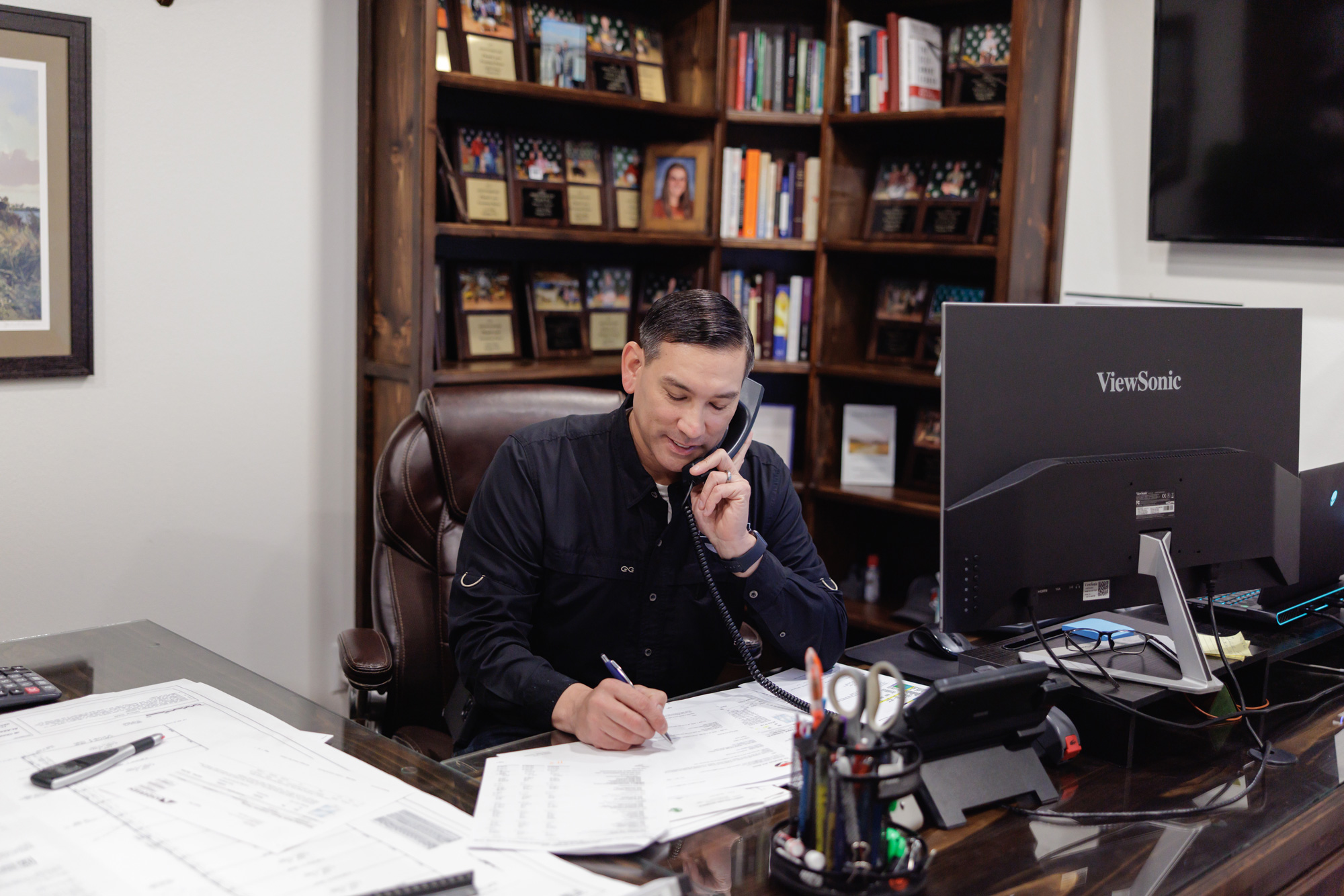 Custom home builder Jake Crawford of JB Crawford Construction talks with a client on the phone as he reviews house plans.