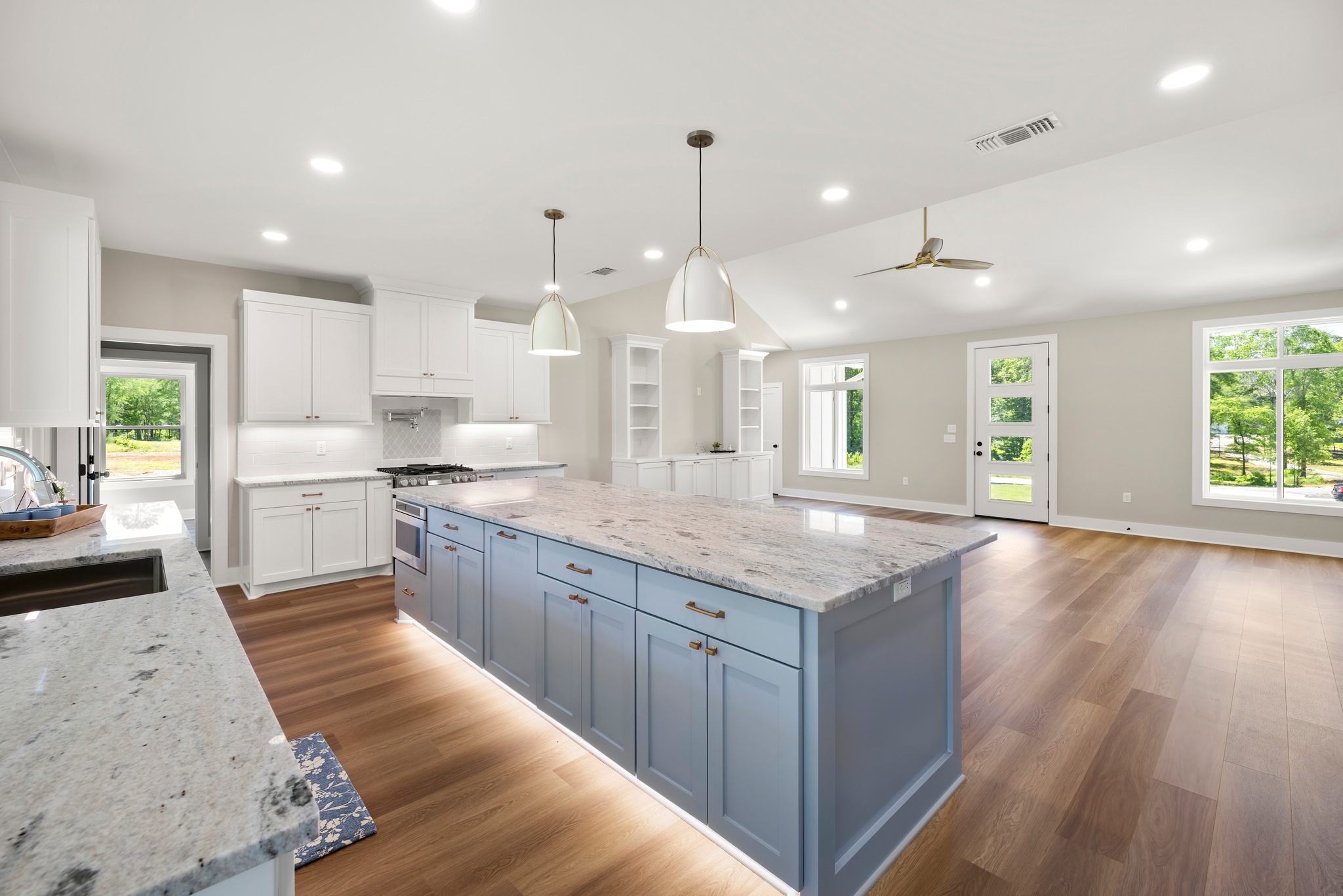 The gourmet kitchen of a JB Crawford Construction custom home is pictured with a striking baby blu island and gas range stove.