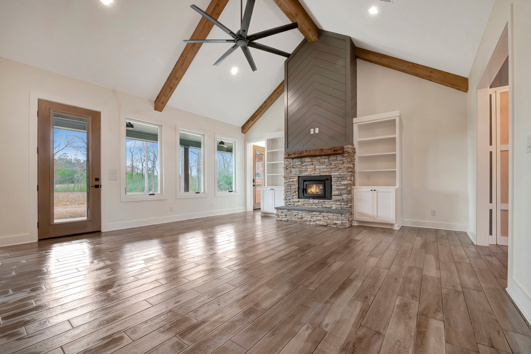A living room built by JB Crawford Construction featuring tall ceilings, beautiful fireplace and mantle, and custom built-ins is pictured.